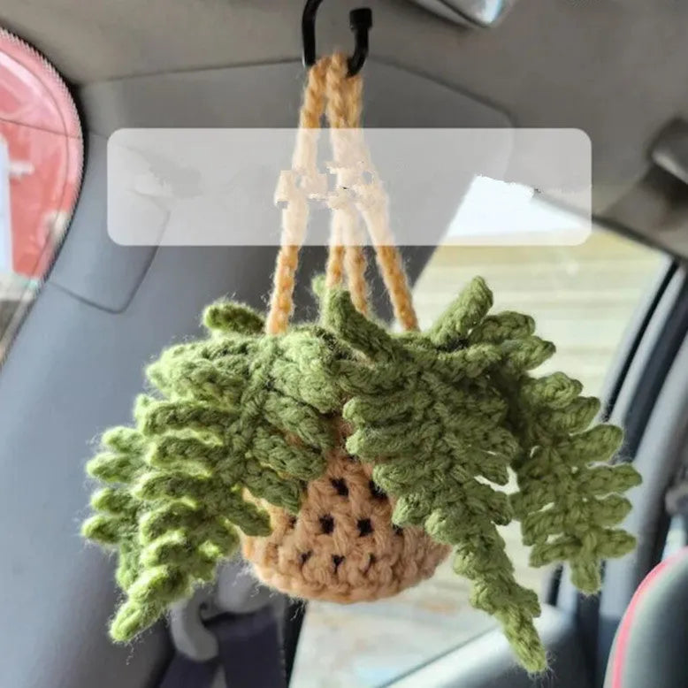 Green and white knitted car plant decoration with hanging rope on car dashboard