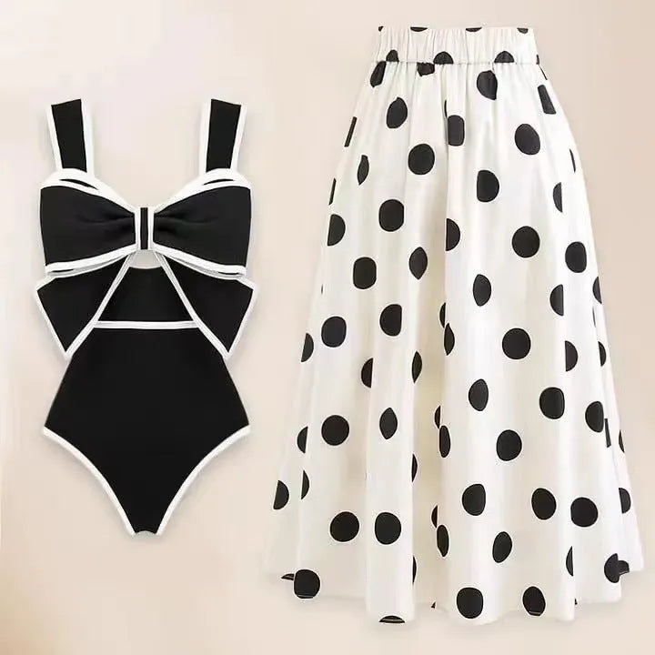 Women's black one-piece swimsuit with a white bow and round skirt on a mannequin, front view.