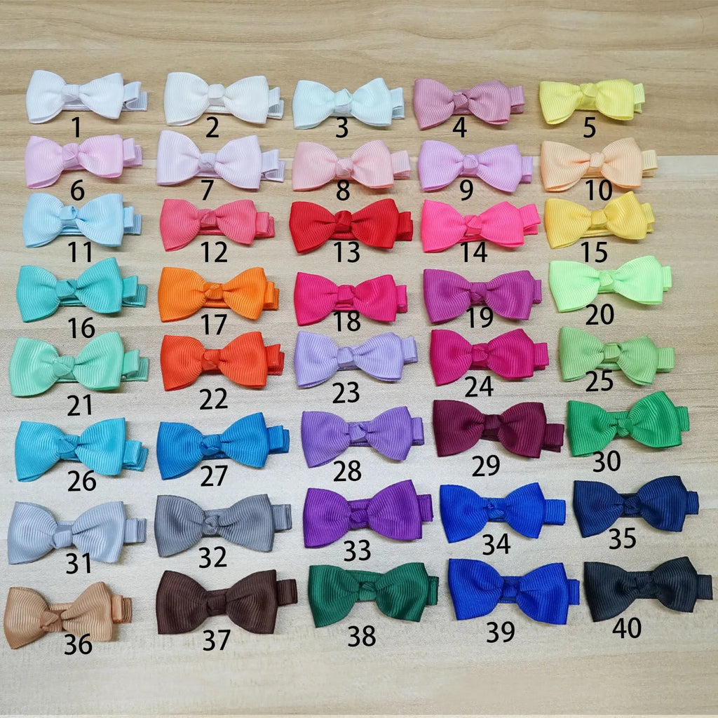 Assortment of pastel-coloured baby hair clips and bows laid out, showing variety of colours.