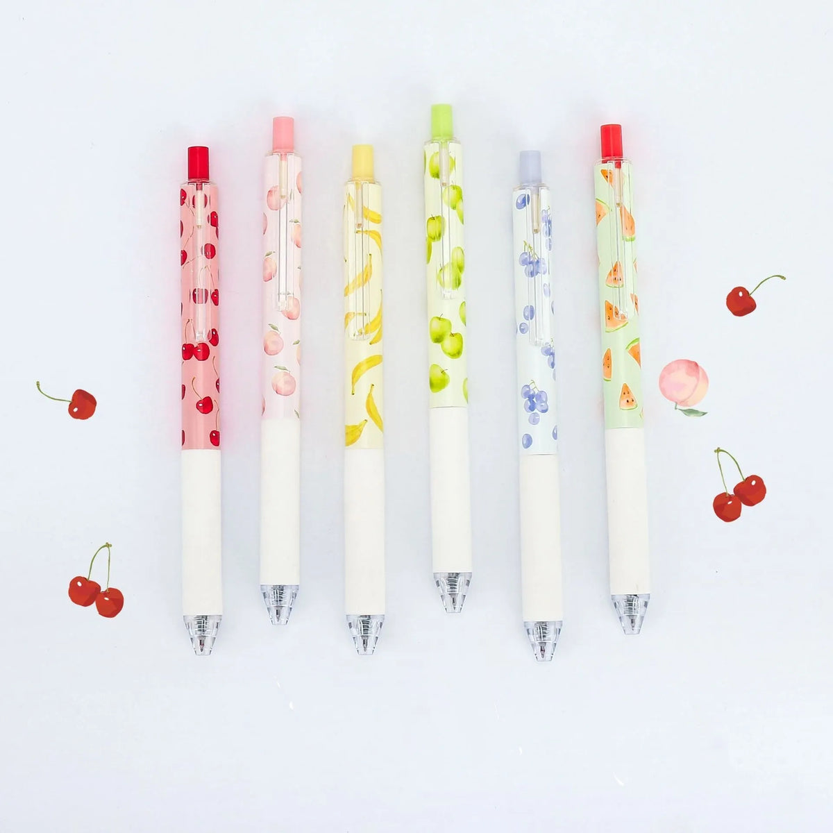 Three fruit-themed scented pressurised pens with 0.5mm black ink refills on writing surface
