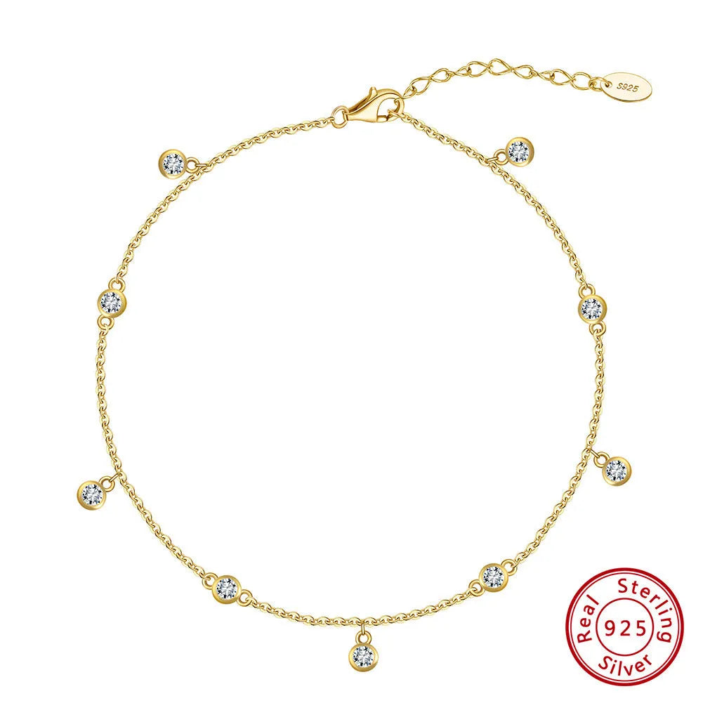 Women's sterling silver geometric zirconium pendant anklet on ankle, showing gold and white gold colour options.