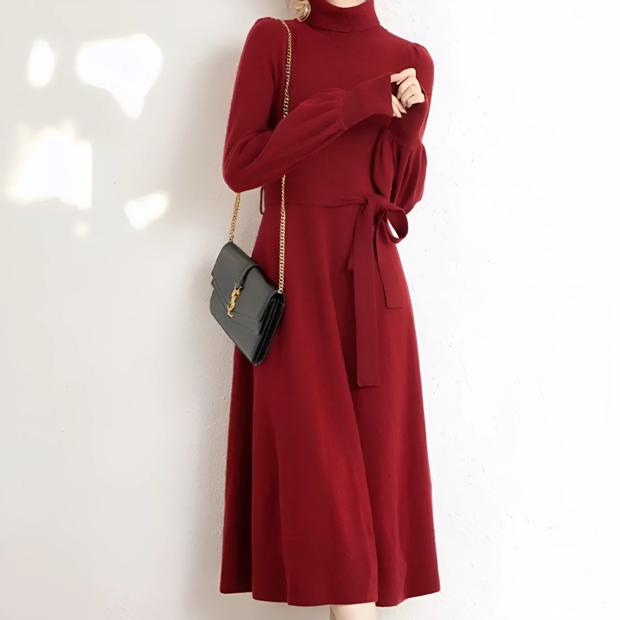 A woman wearing a rose red knitted turtleneck sweater dress with long sleeves, an elastic waist, and a loose, big hem.