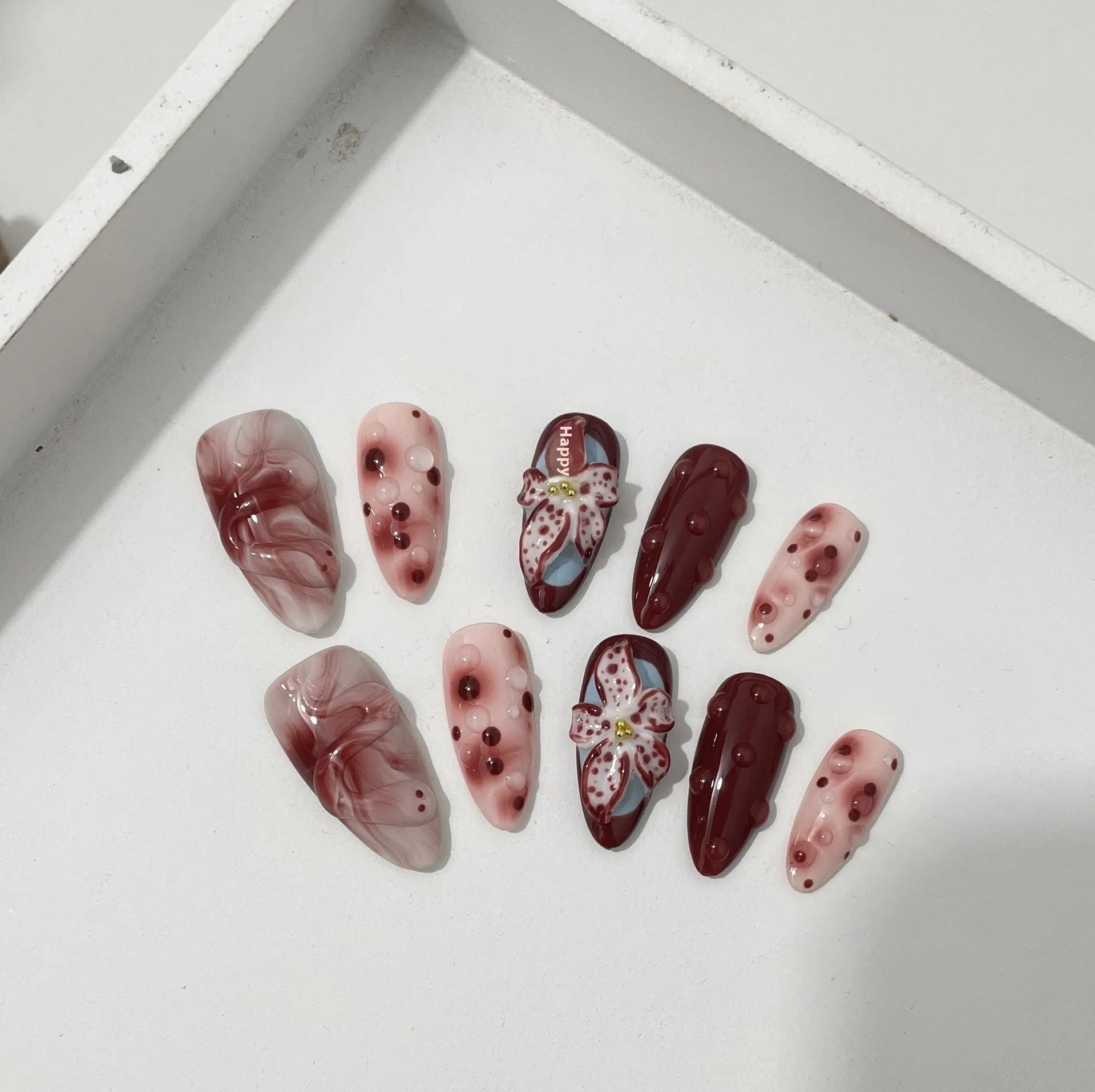 Almond shaped false nails with hand-painted 3D carved rose and tulip designs on a medium length nail.