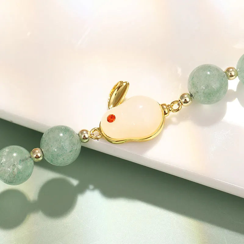 Women's rabbit charm bracelet with green aventurine stones and silver and gold plated metal links.