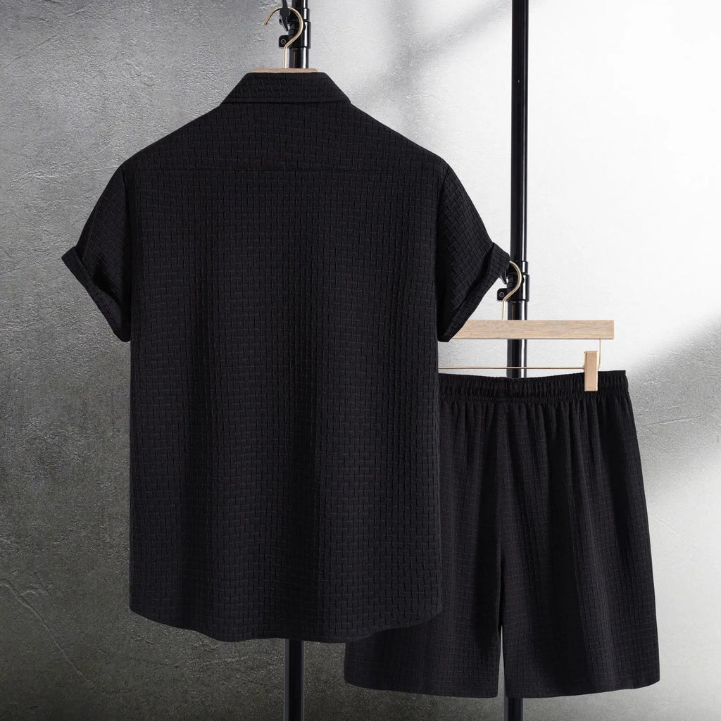 Men's loose-fitting cotton blend short sleeve shirt and shorts suit in black, laid flat.