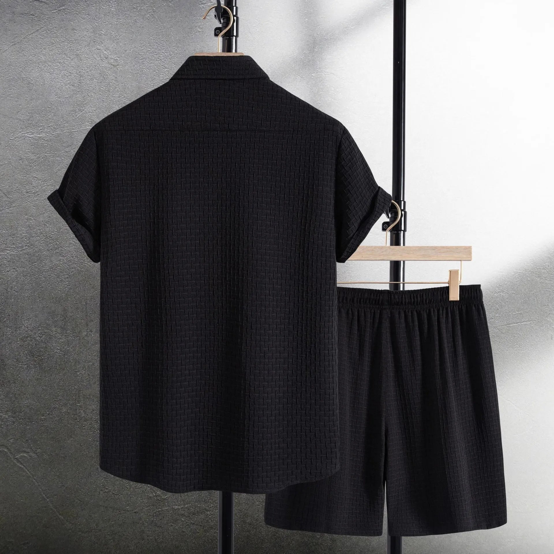 Men's loose-fitting cotton blend short sleeve shirt and shorts suit in black, laid flat.