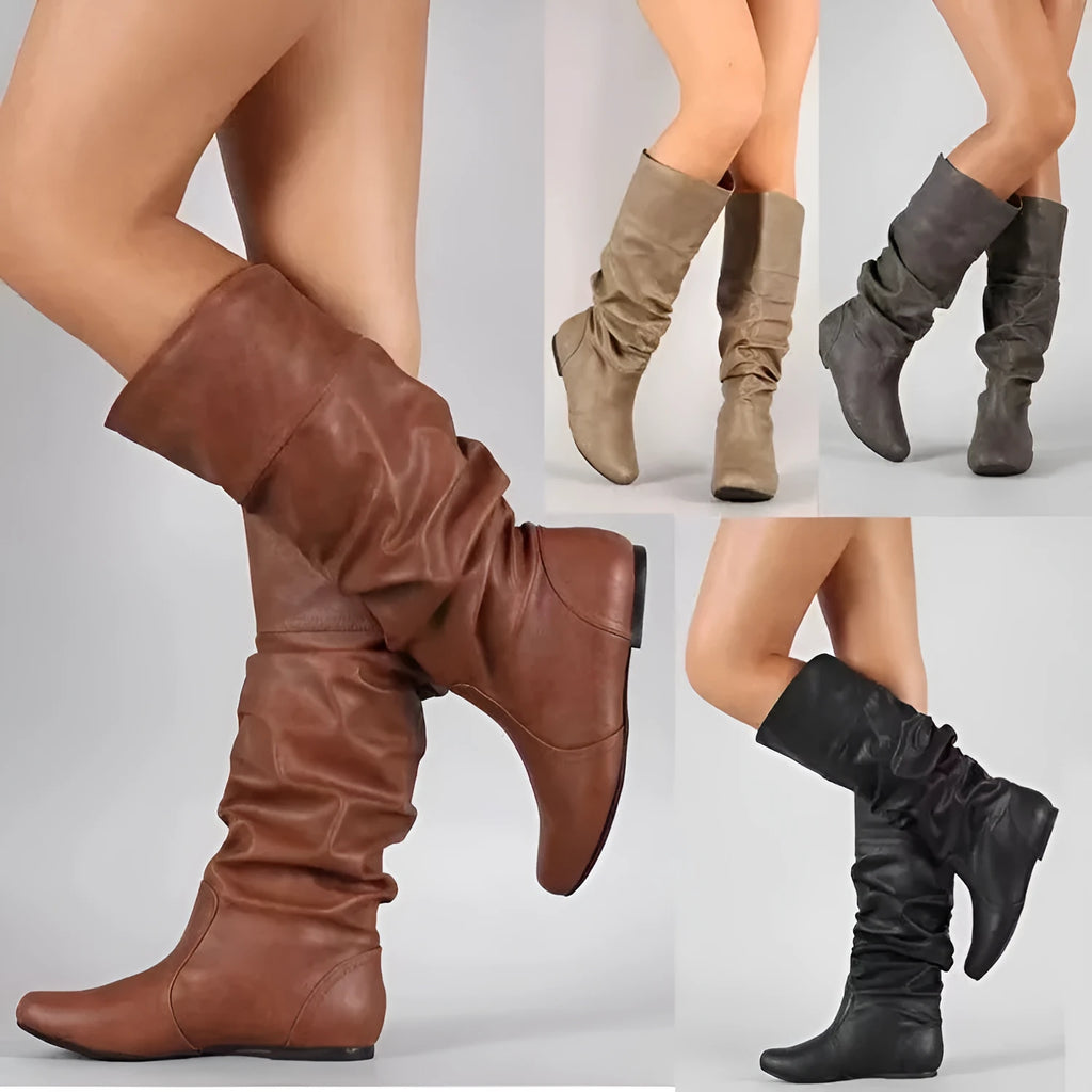 Women's black slip-on flat long boots with a round toe and high shaft on a neutral background.
