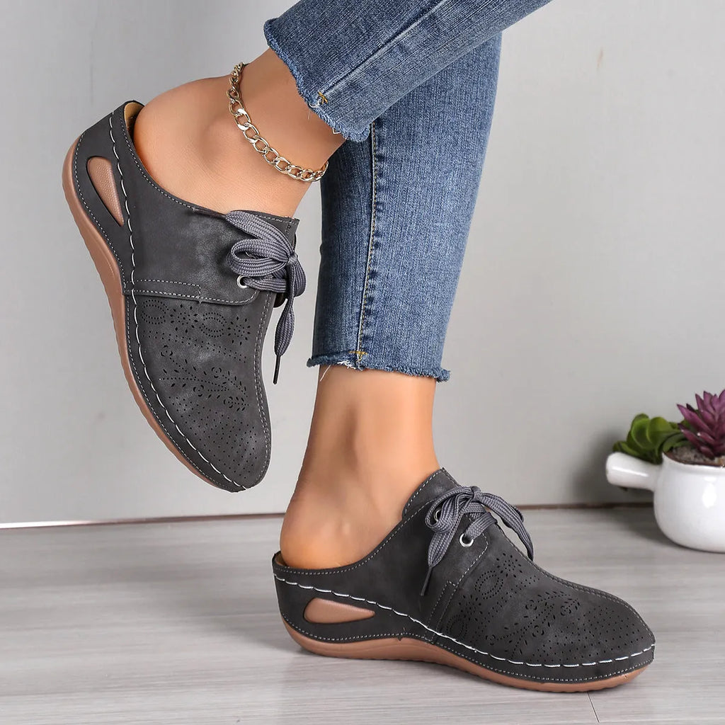 Women's black lace-up wedge slippers with a suede upper and hollow-out rubber sole on a light background.
