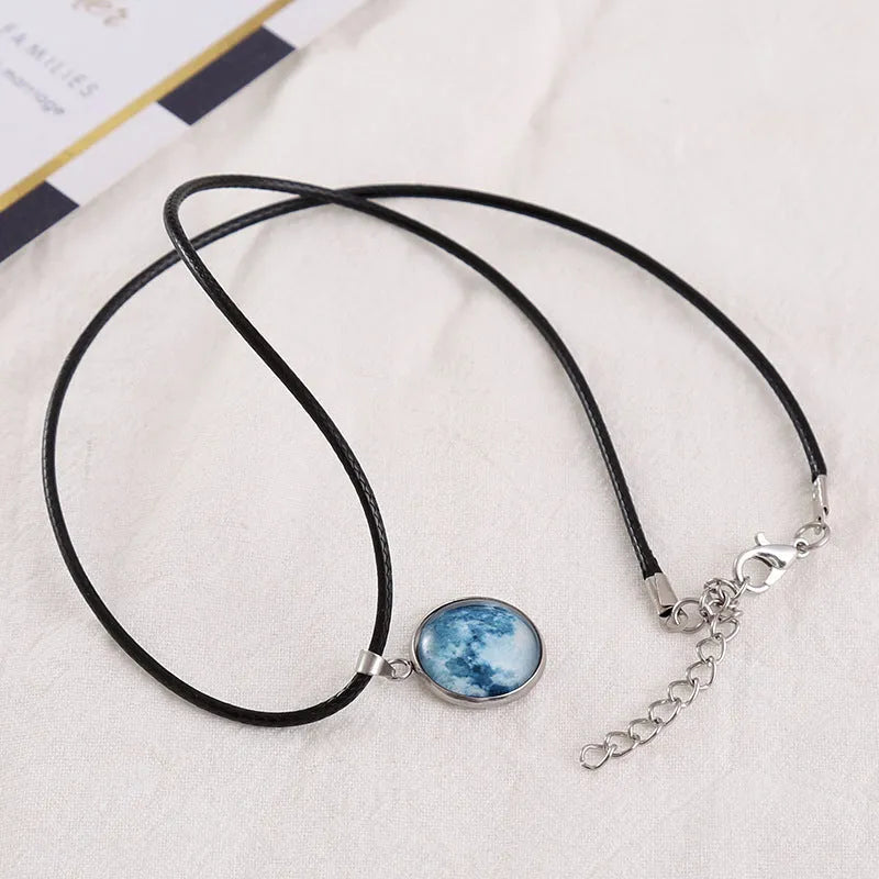 Close-up of a luminous alloy necklace with a blue organic glass constellation pendant on a model.