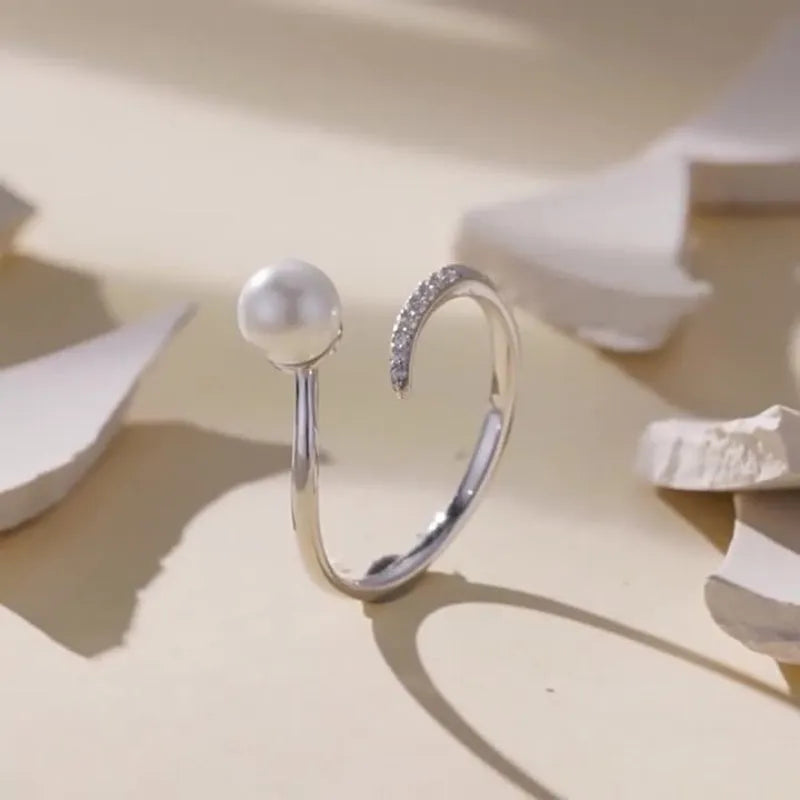 Adjustable sterling silver ring for women with a central shell pearl on an open-loop band.