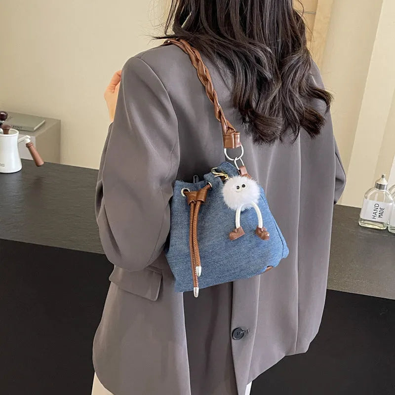Blue synthetic leather cross-body bucket bag with adjustable strap and optional hanging drop decoration