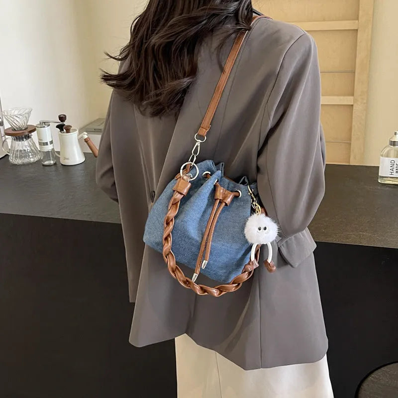 Blue synthetic leather cross-body bucket bag with adjustable strap and optional hanging drop decoration