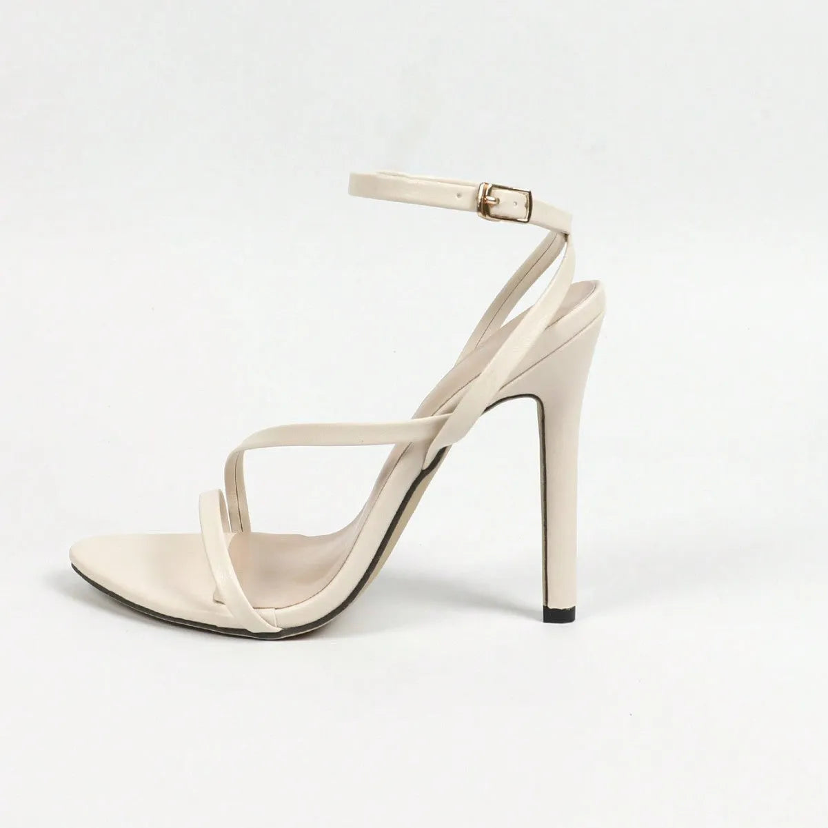 Women's gold sandals with cross ankle straps and open toe design on wooden floor