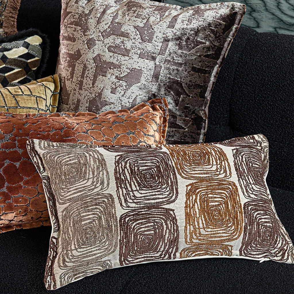 Square and rectangular pillow covers with cream and coffee abstract coil pattern on a sofa.