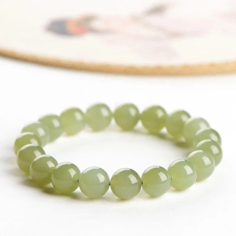 Hetian jade ball bracelet on wrist showing polished spherical beads on an elasticated string in a clear colour.