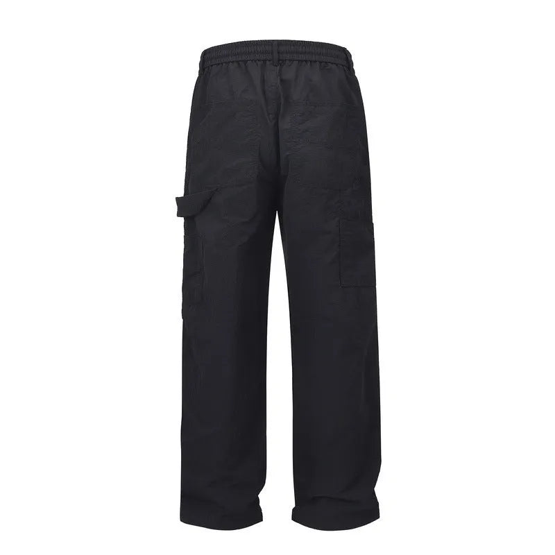 Black paratrooper trousers with elastic waist and drawstring closure, showing baggy fit and three-dimensional cutting