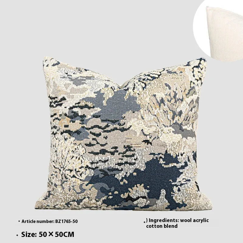 Antique blue French style decorative pillow with abstract floral pattern on a sofa.