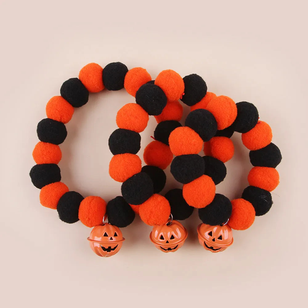 Orange Halloween cat collar with a pumpkin graphic and metal jingle bell on a black background.
