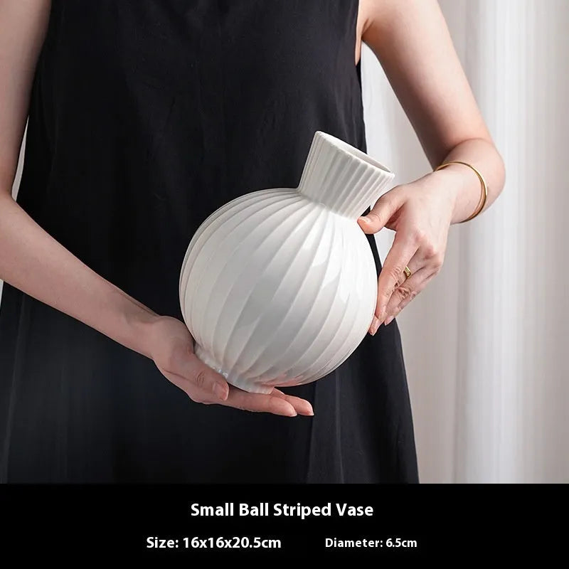 White ceramic ball-shaped vase with striped American country design on a table.