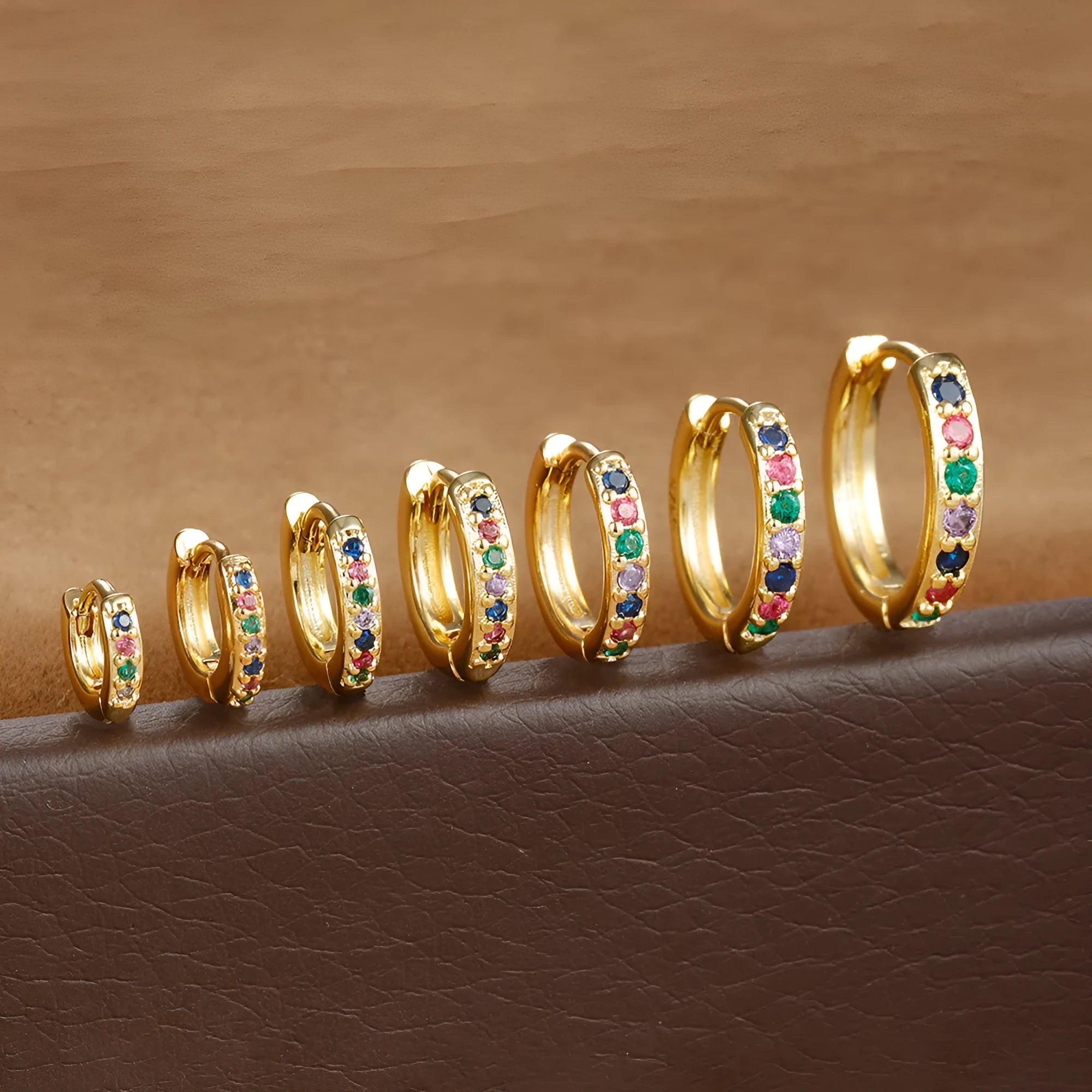 A pair of small circular zircon stud earrings with a metallic finish, shown next to a ruler indicating available sizes from 5mm to 12mm.