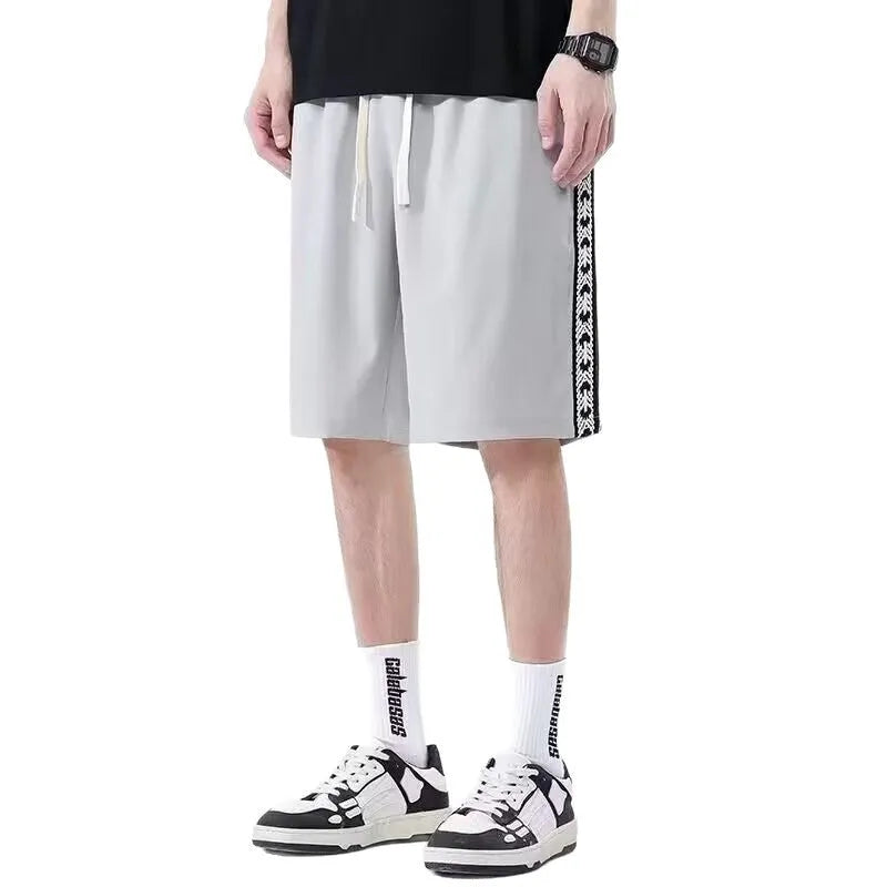 Men's loose-fitting black baggy track pants with a sports style on a plain background.