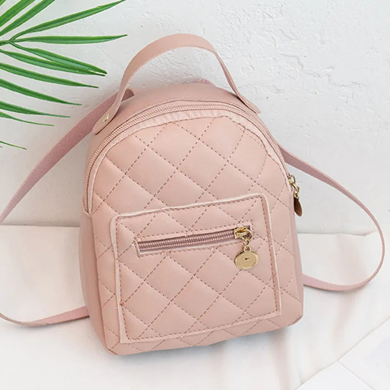 Hard-sided square pink backpack with embroidered detail, shown with soft carry handle and straps.