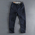 Men's khaki cotton work trousers with mid waist and zipper fly on a neutral background