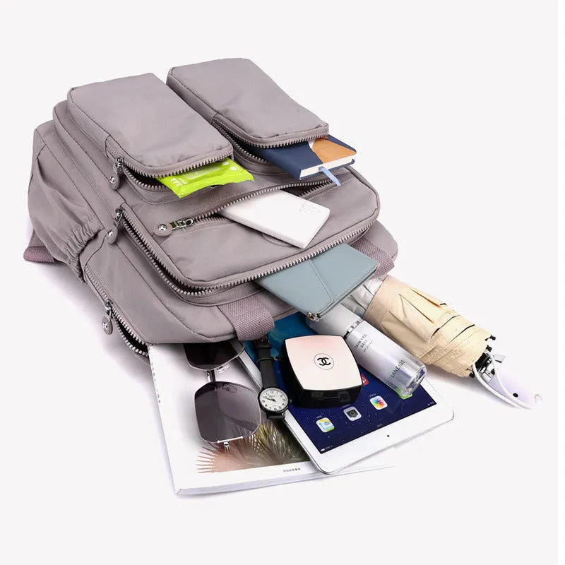 Waterproof women's travel backpack in grey showing front three-dimensional pocket and internal organiser compartments.