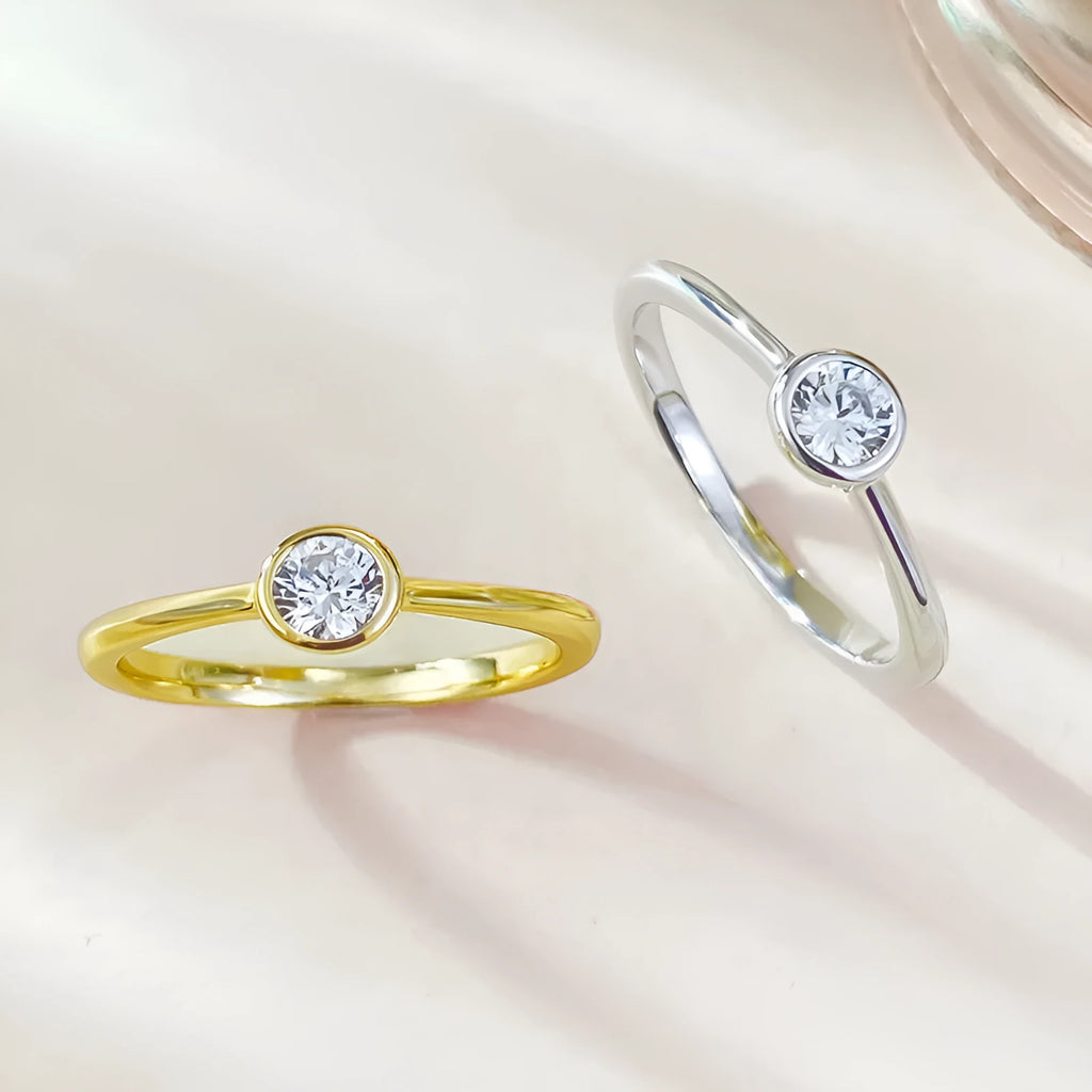 Minimalist crown shape silver ring electroplated in gold or platinum colour on a plain background.