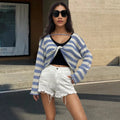 Black and white striped cropped sweater with long sleeves on a woman, showing exposed navel detail.