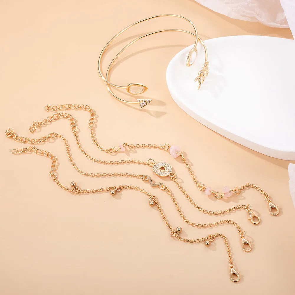 Gold zinc alloy bracelet set with six charms including spot drill, arrow, and water drop shapes.