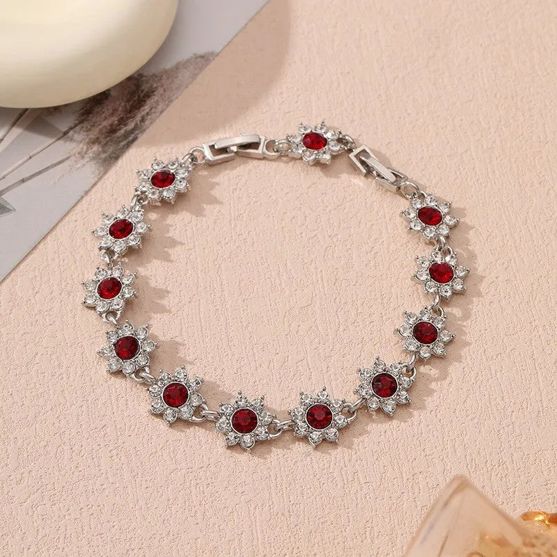 Gold tone flower-shaped bracelet with blue crystal gems on a wrist.