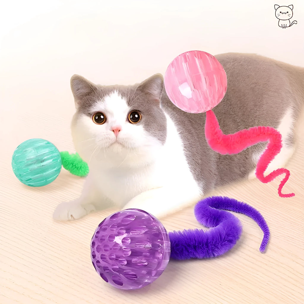 Green TPR bouncy cat toy with a long plush tail on a wooden floor.