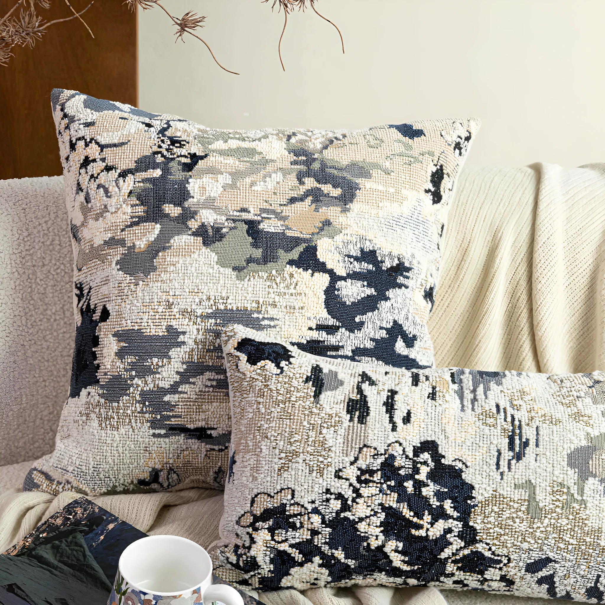 Antique blue French style decorative pillow with abstract floral pattern on a sofa.