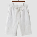 Men's beige linen shorts with loose cropped fit and elasticated waistband laid flat.
