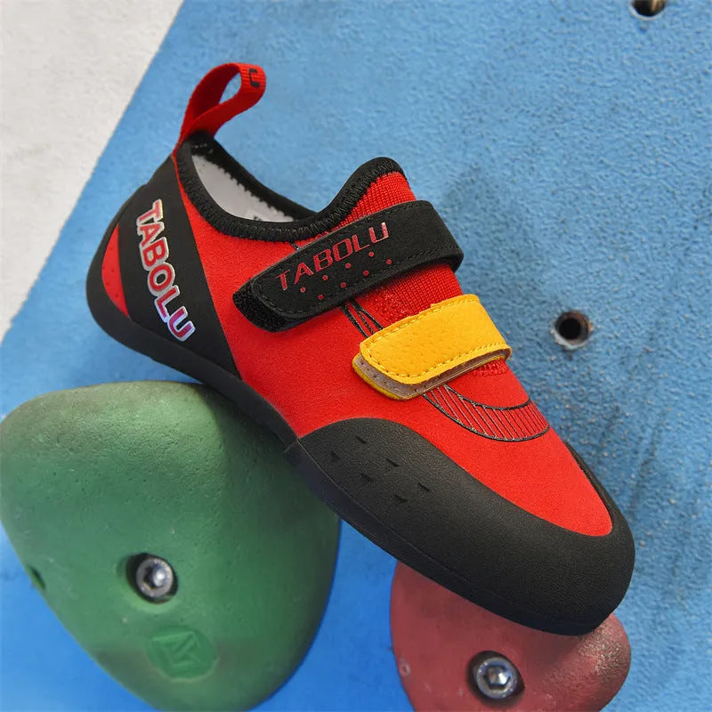 Black beginner rock climbing shoes with Velcro straps and a coloured accent on a rubber sole.