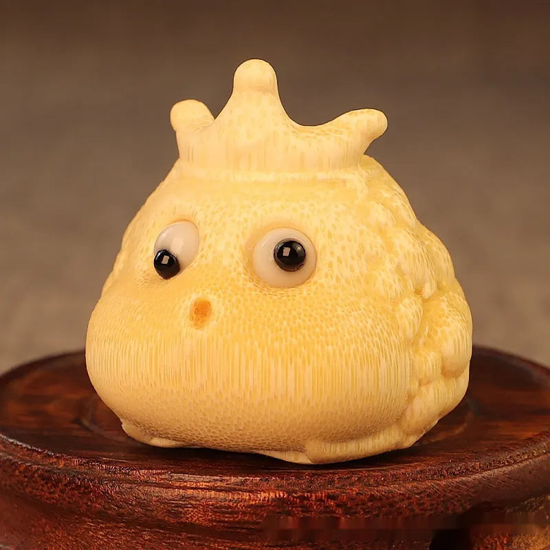Close-up of a hand-carved bamboo Crown Princess toad ornament with live eye detailing.