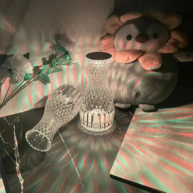 White crystal vase-shaped table lamp with remote control on a wooden surface.