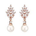 Geometric flower shaped earrings with micro inlaid zircon stones and pearl accents on a gold plated background.