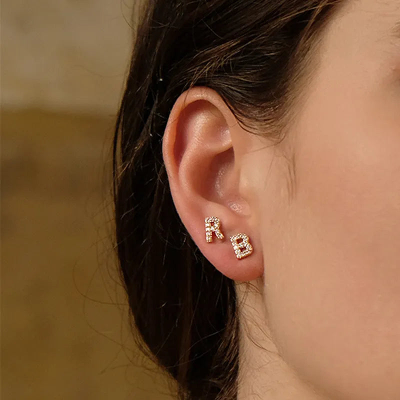 A single gold plated earring shaped like the letter A, set with small sparkling zircon stones.