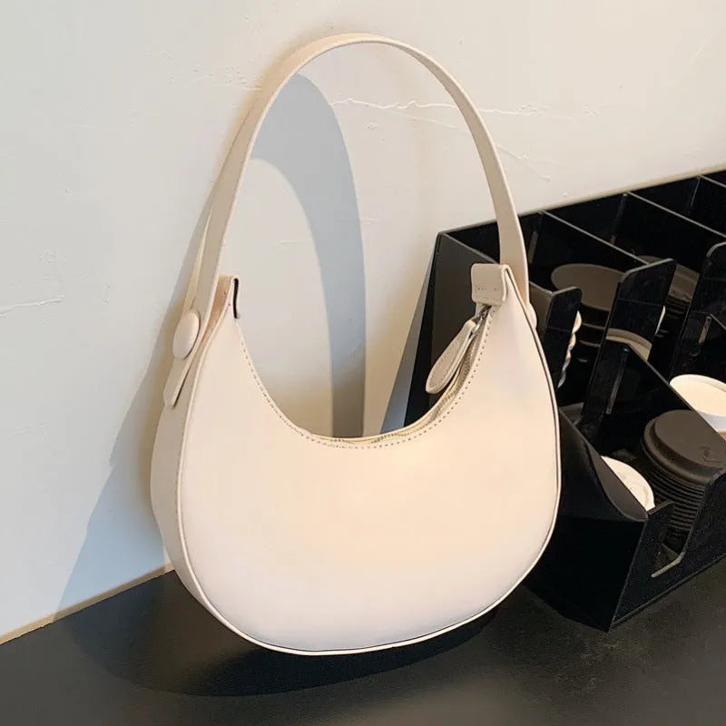 Women's retro-style dumpling-shaped PU leather shoulder bag in cream yellow, showing sandwich pocket.