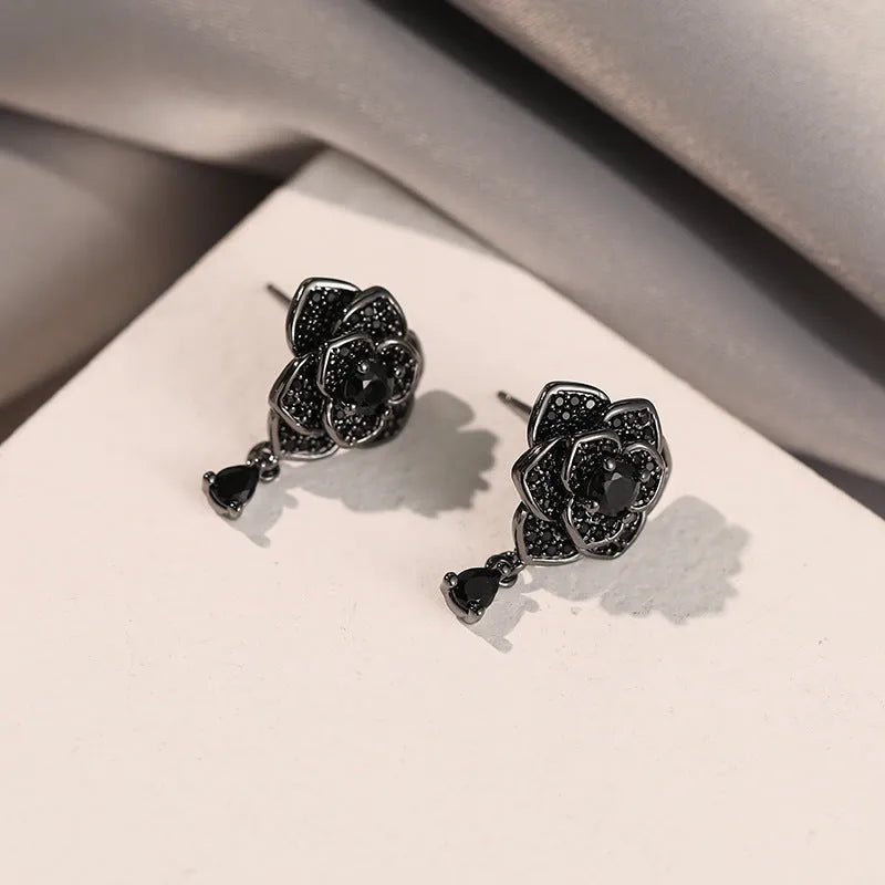 Close-up of women's floral stud earrings with a black rose zircon stone and gold electroplated finish.