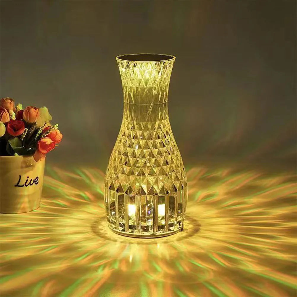 White crystal vase-shaped table lamp with remote control on a wooden surface.