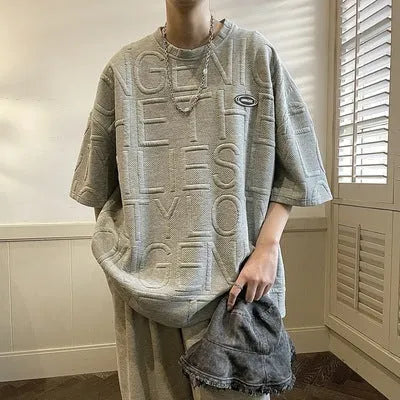 Grey men's loose fit t-shirt with a retro-style three-dimensional raised letter print on the front.