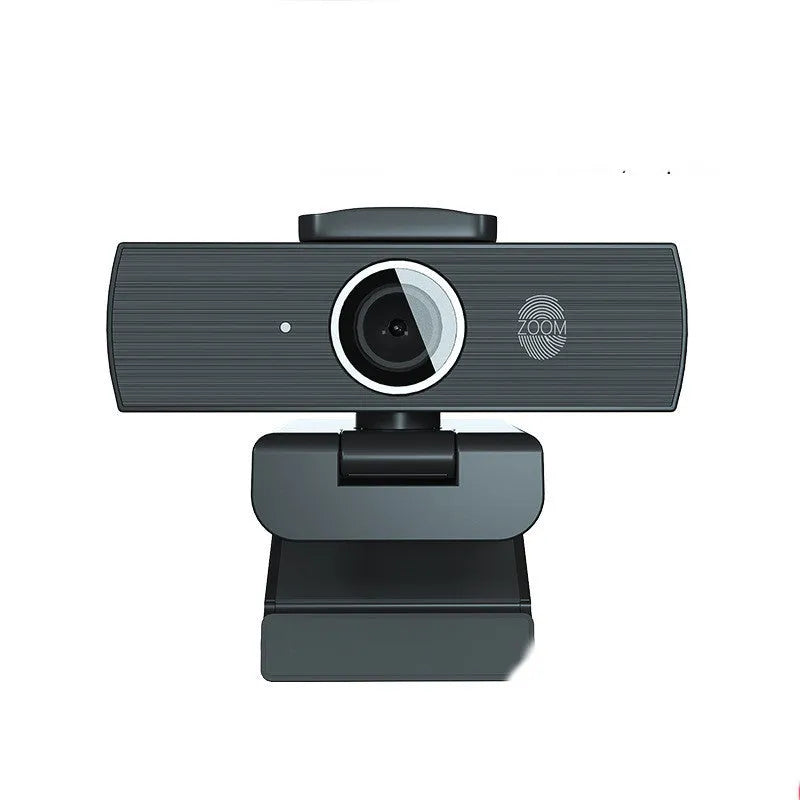 Black USB computer webcam with attached cable and magnetic privacy cover on a desk