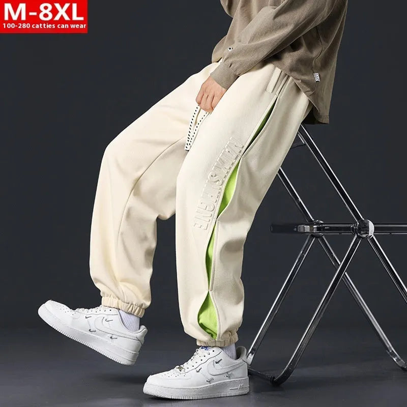 Man wearing loose grey-green cotton trousers with a banded ankle cuff and stitching detail.