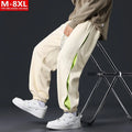 Man wearing loose grey-green cotton trousers with a banded ankle cuff and stitching detail.