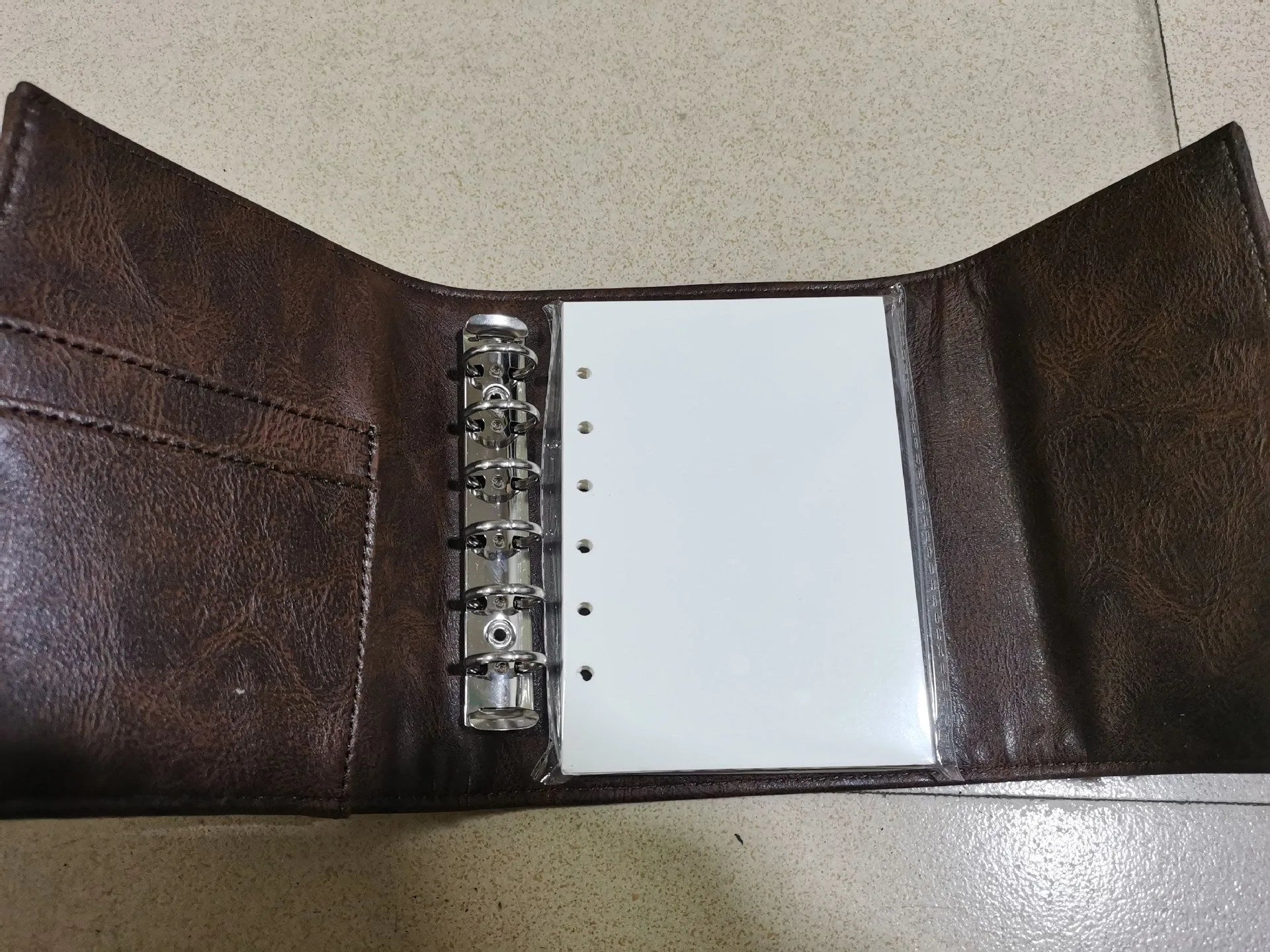 Brown retro-style notebook with leather buckle on PU cover, showing loose-leaf binder binding and A7 size