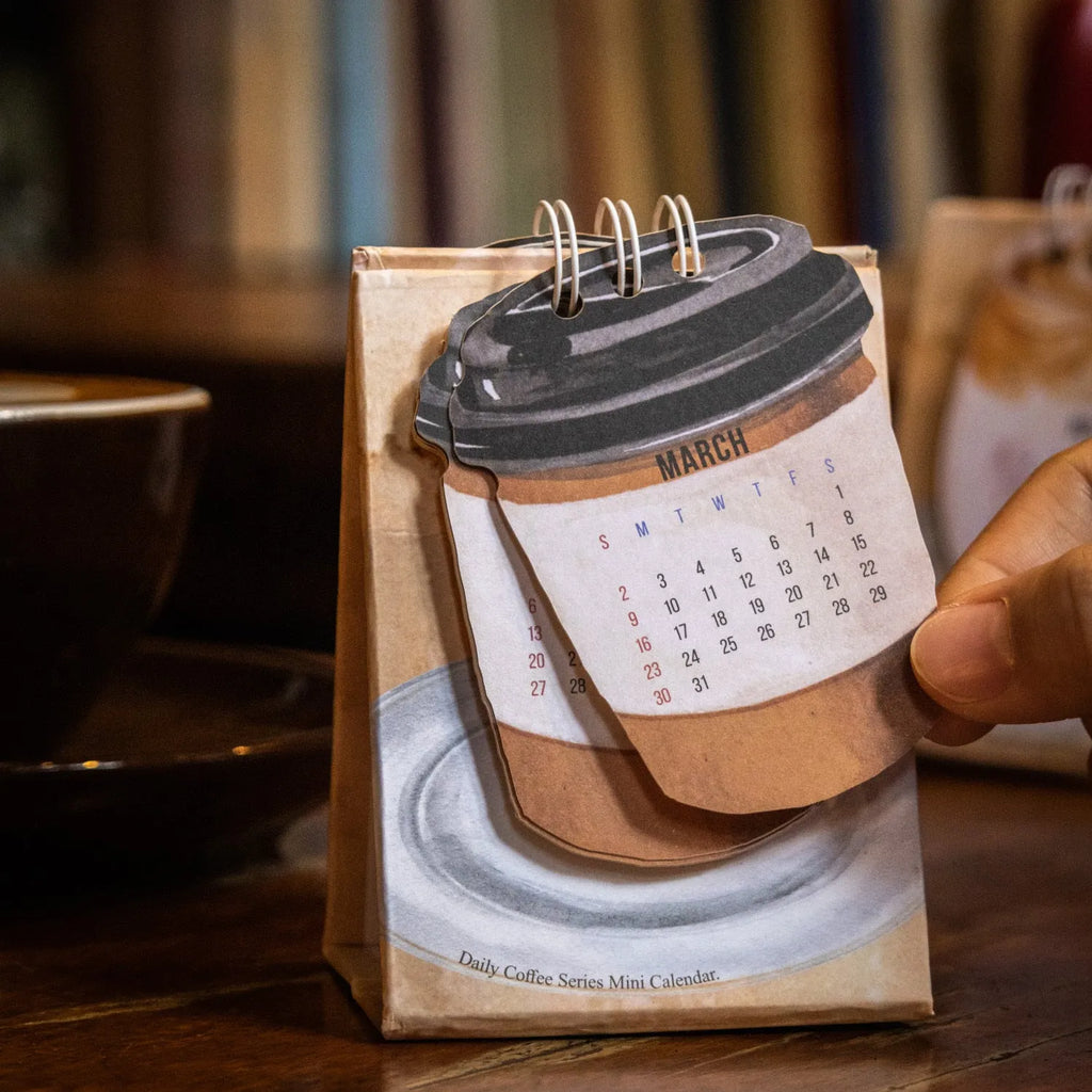 Mini coffee-themed desk calendar showing 2025 dates with motivational text
