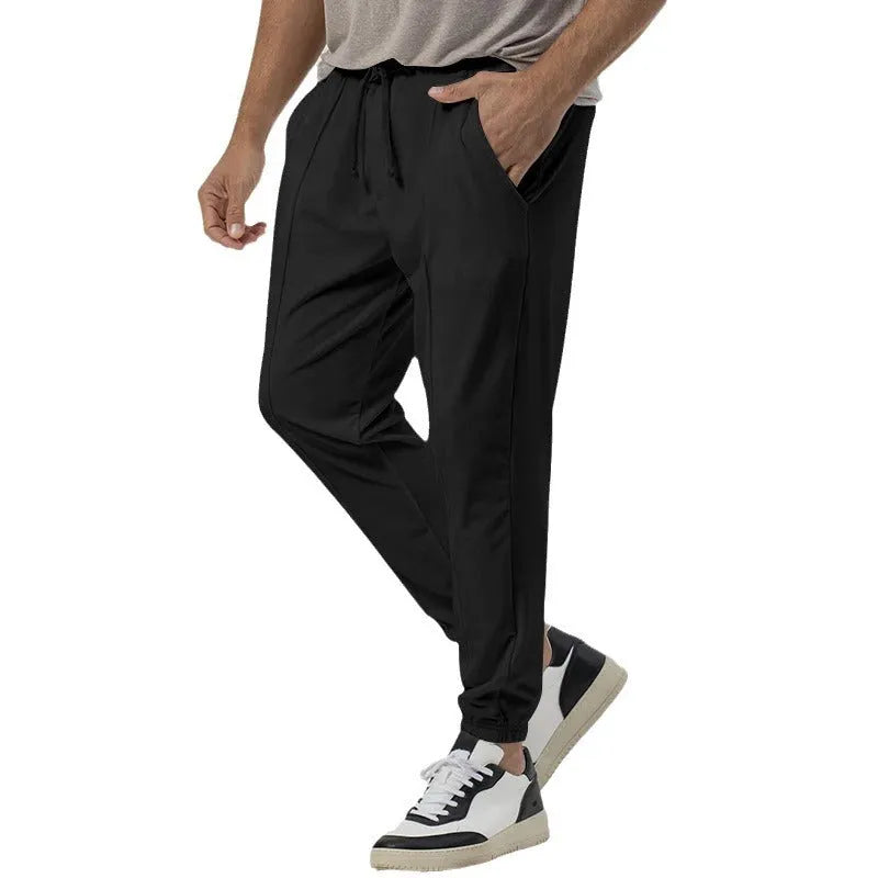 Men's grey cotton blend straight-leg track sweatpants with a mid waist and loose tapered fit on a hanger.